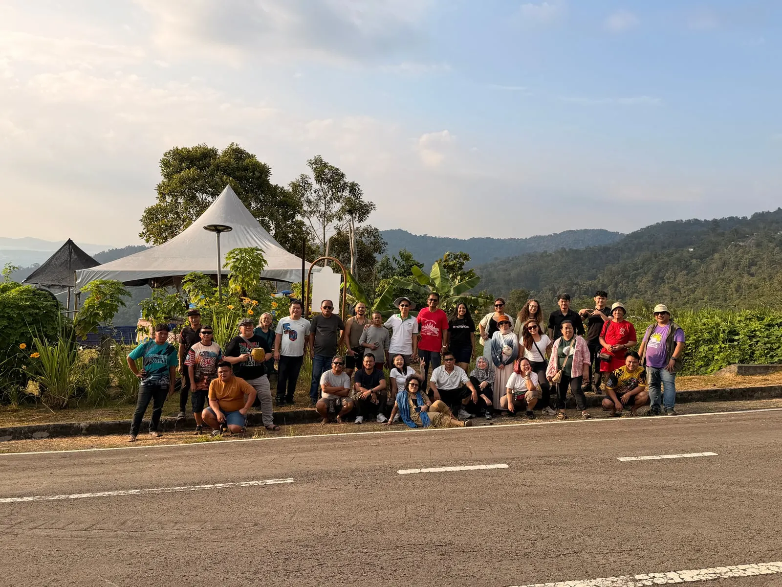 The group photographed at a roadside viewpoint above forested hills at the end of the day