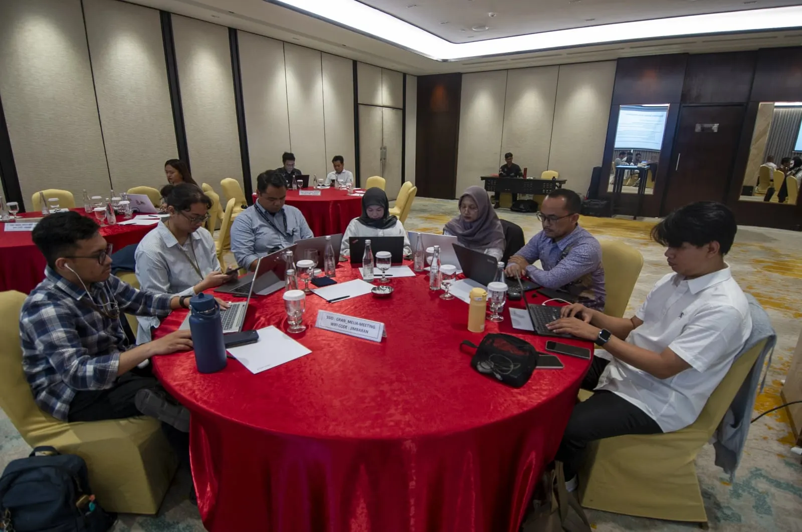 Participants working at a round table with laptops during a breakout session at the dialogue