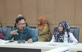 A participant gesturing as he speaks during the discussion, with others listening beside him