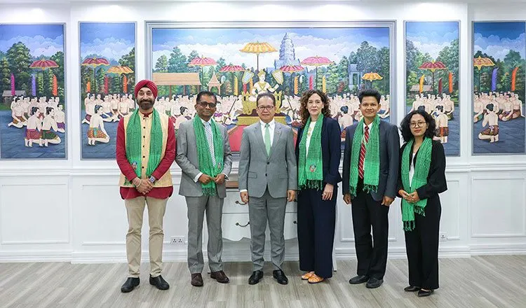 Cambodia's Environment Minister Eang Sophalleth with a Fossil Fuel Treaty delegation, all wearing green krama scarves, in front of a large mural