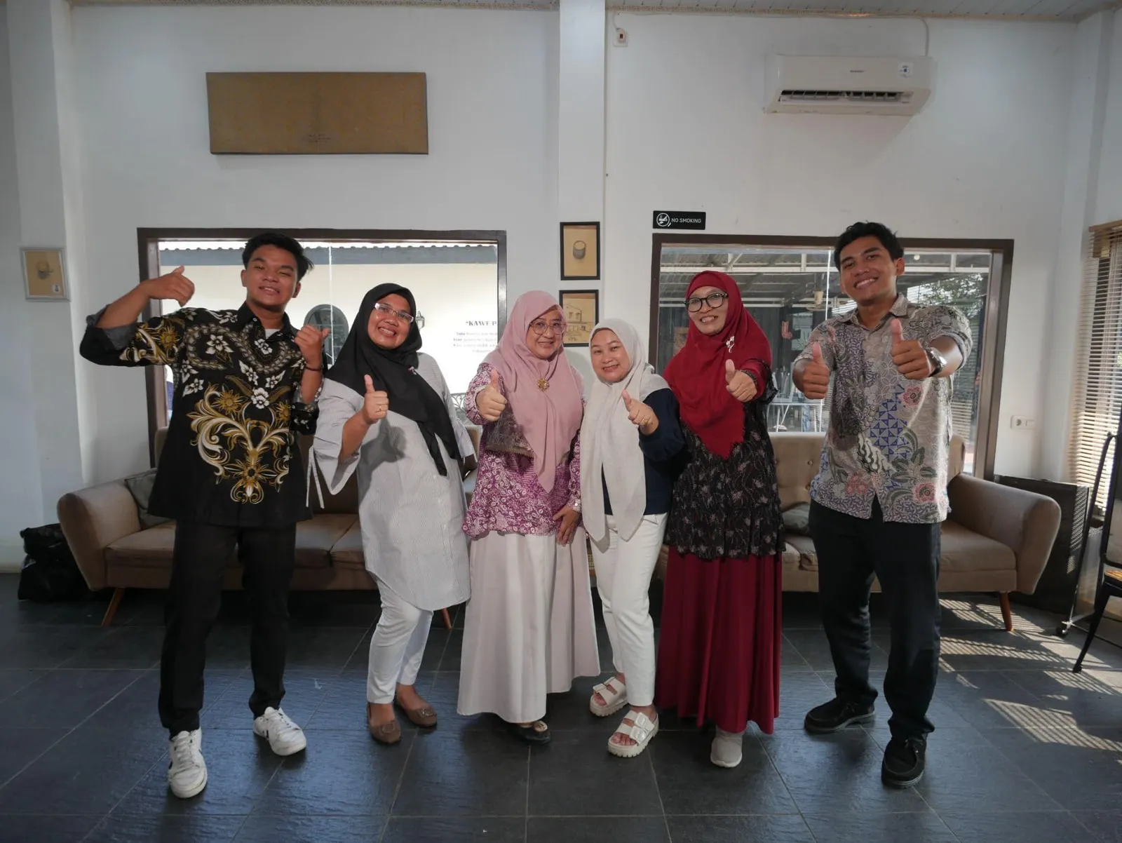 Six members of the YMH South Sumatra team standing together in a café, thumbs up